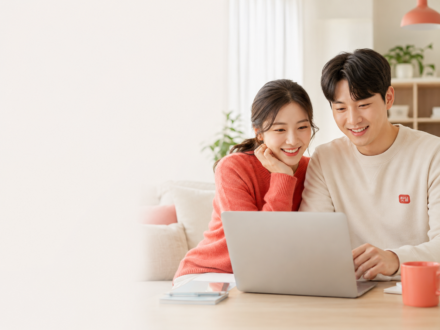 밝은 거실에서 한국인 커플이 노트북으로 다양한 생활서비스를 비교하는 모습